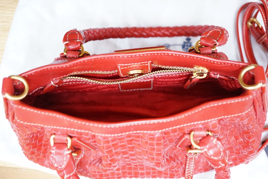 A Prada red braided leather handbag with shoulder strap, authenticity card and dust cover, 25cm wide, Provenance: Purchased by the vendor in Selfridges